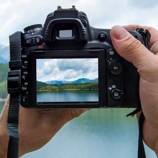 Hände halten eine Kamera, die ein Bergmotiv auf dem Display zeigt. Foto: JDAV/Adobe Stock