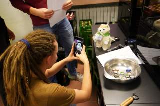 Person hält Smartphone in die Höhe, um ein Kuscheltier zu fotografieren
