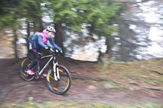 Eine Junge Frau fährt schnell mit dem Mountainbike durch einen Wald
