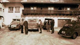 Ein altes Foto; Eine kleine Gruppe steht vor einem typisch bayrischen Haus und unterhält sich