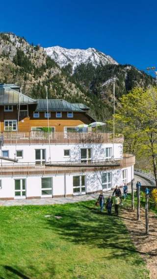 Eine Jugendherberge mit großem Außenbereich; im Hintergrund die Berge