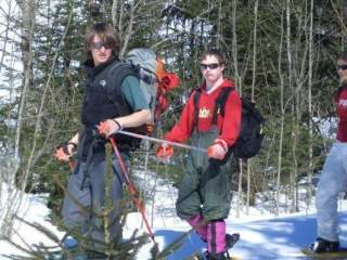 Zwei Jugendliche wandern zusammen durch einen verschneiten Wald; einer der beiden lebt mit einer Behinderung