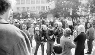 Ein Demonstrant wird von vier Polizisten festgehalten; um ihn herum eine Menschenmenge