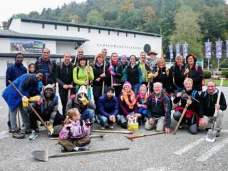 Ein Gruppenfoto von einer Menschengruppe vor ihnen liegen Schaufeln