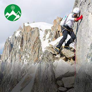 Eine Bergsteigerin klettert gesichert an einem steilen Felsvorsprung in den Alpen.