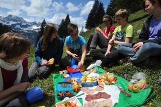 Eine Jugendgruppe macht ein Picknick auf einer Bergwiese