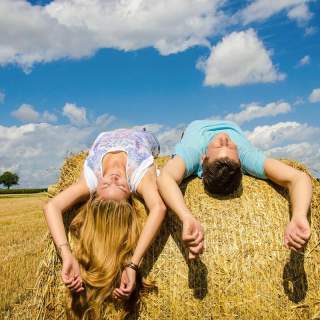 Zwei junge Menschen liegen auf einem Heuballen und genießen die Sonne