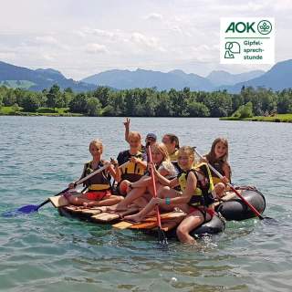 Eine Gruppe junger Mädchen sitzt auf einem Floß auf einem See