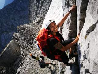 Frau, die im Gebirge klettert und lacht