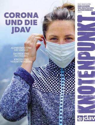 Eine Frau in einer lilanen Strickjacke, die sich eine Corona-Maske aufsetzt