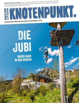 Ein Mädchen, das in einem Klettergarten klettert; Im Hintergrund die Jugendbildungsstätte Bad Hindelang und Berge