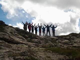 Eine Jugendgruppe steht freudig am Berg