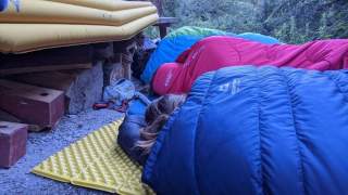Jugendliche im Schlafsack liegen in den Bergen