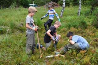 Vier Kinder arbeiten mit Gartenwerkzeug im Moor