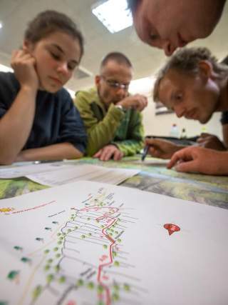 Eine Gruppe studiert eine Bergkarte und verschiedene Routen