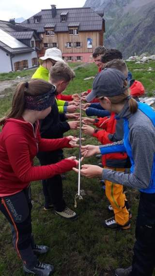 Kursteilnehmende bei einer Übung zum Teamwork: Es muss eine Stange balanciert werden d