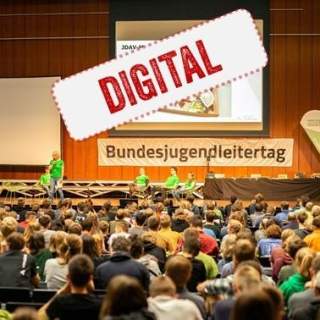 Ein großer Saal voll mit Leuten und einer Bühne