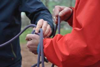 Hände werden mit Kletterseilen verbunden