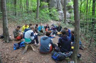 Eine Jugendgruppe sitzt in einem Kreis zusammen im Wald